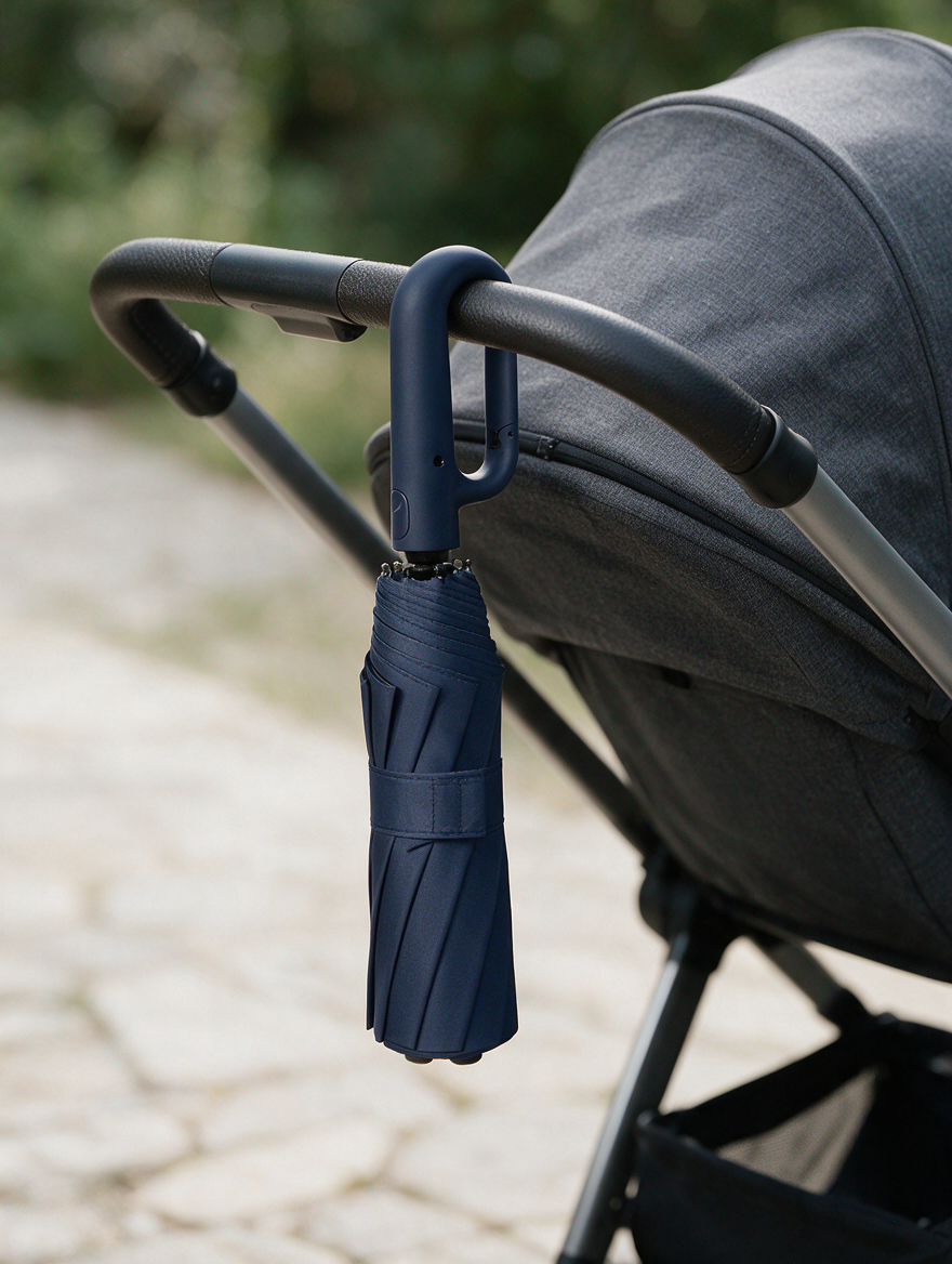 Ombriel Loop umbrella in navy clipped by its ring handle to a pram handlebar